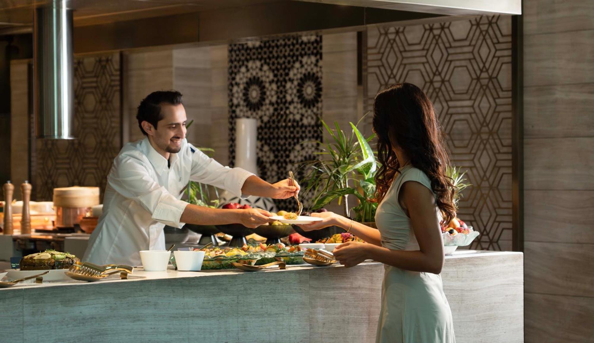 Fairmont Riade Exterior foto A chef serving a guest at the buffet